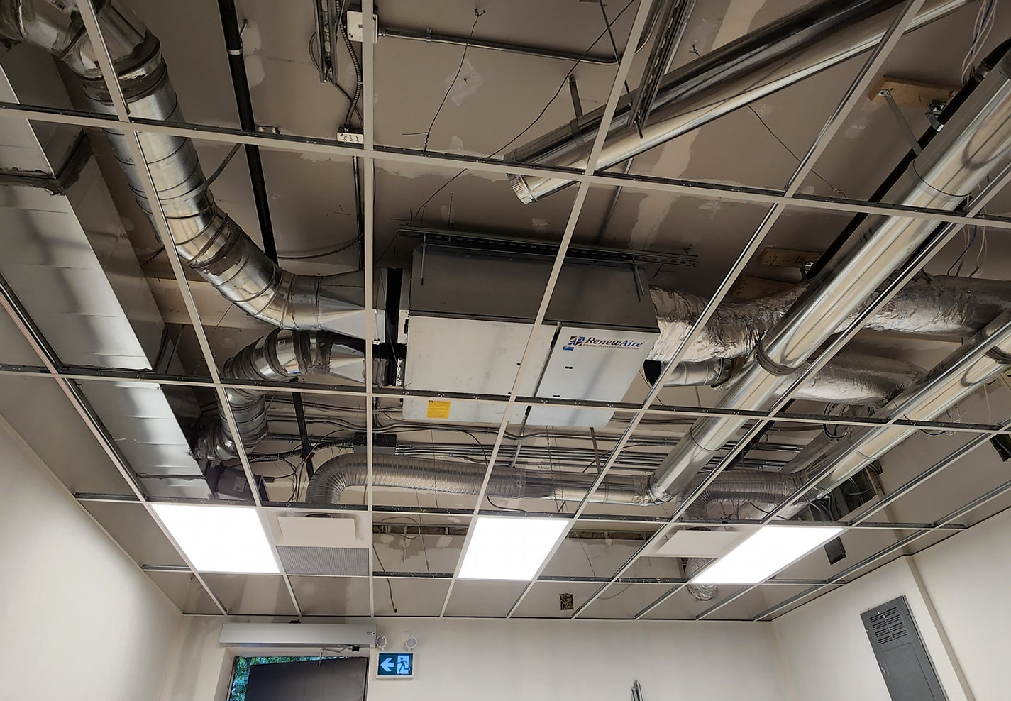 Exposed building services above a ceiling grid in Schomberg