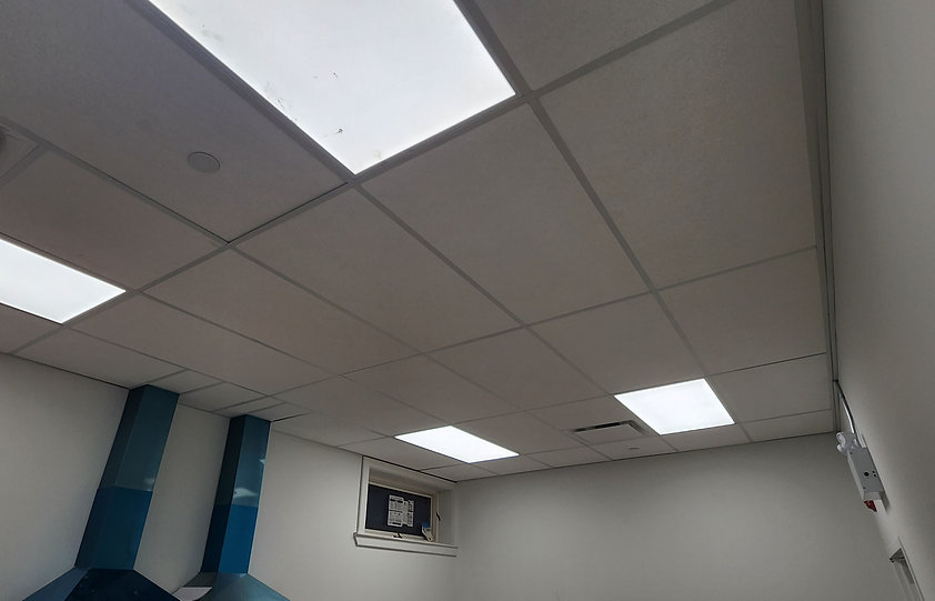 Suspended ceiling tiles and rectangular lights above blue exhaust hoods at Schomberg Community Hall